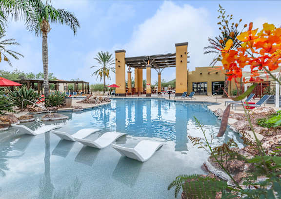 A pool with loungers and a building in the background.
