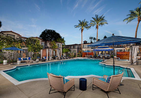 Two chairs are placed on the ground near a swimming pool.