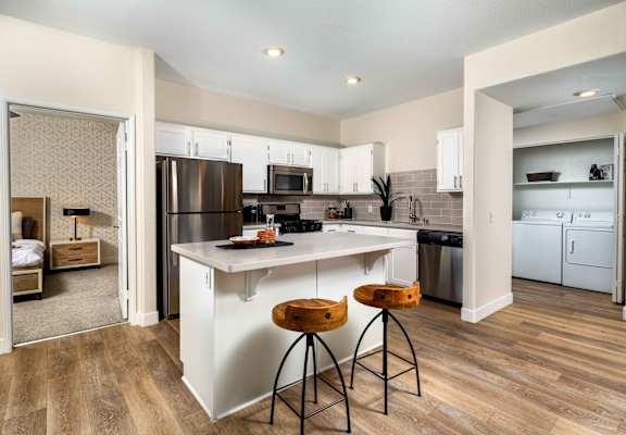 A kitchen with white cabinets and a wooden floor.