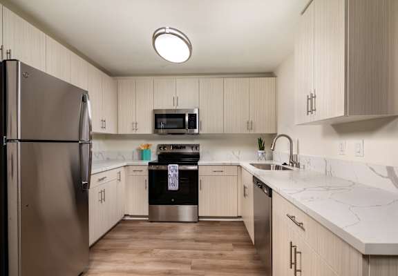 A kitchen with a refrigerator on the left and a sink on the right.
