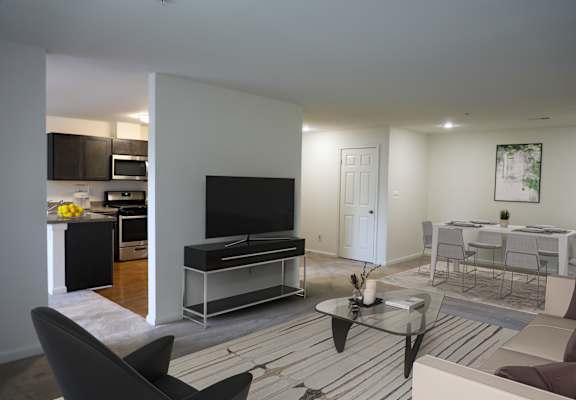 A modern living room with a black sofa and a glass coffee table.
