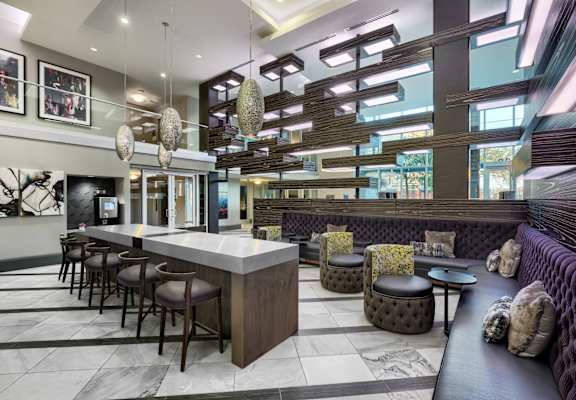 A modern bar with a long counter and a row of stools.