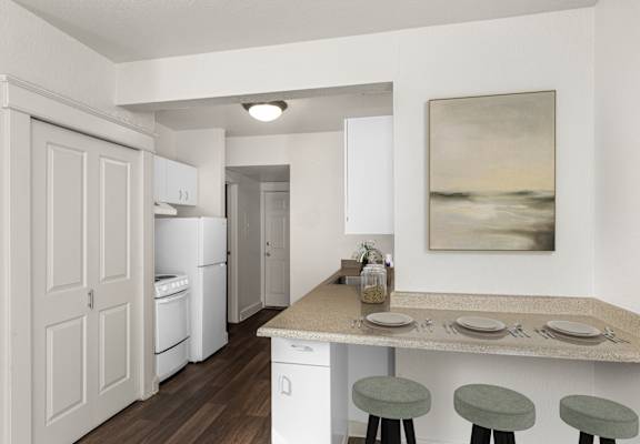 A kitchen with a table set for two with a painting hanging on the wall.