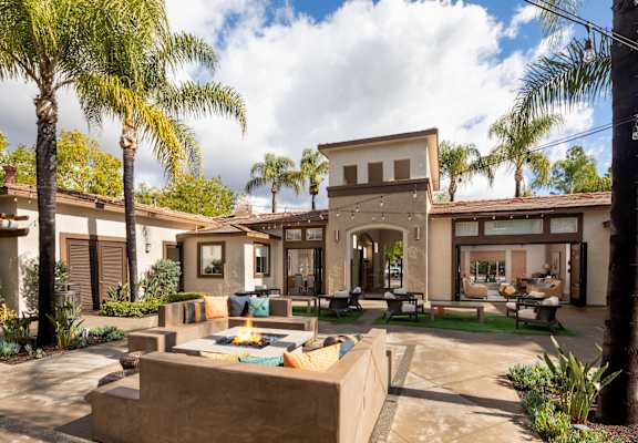 a patio with a fire pit in front of a house