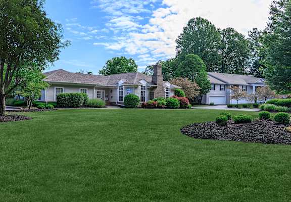 a lush green lawn with two houses in the background