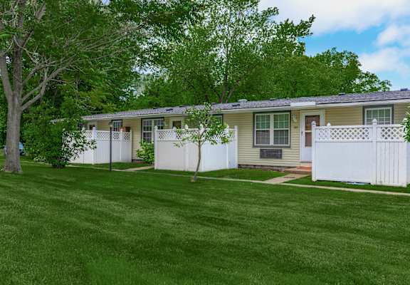 a mobile home with a white fence and green grass