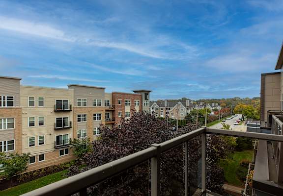 A balcony overlooks apartment buildings and a street.