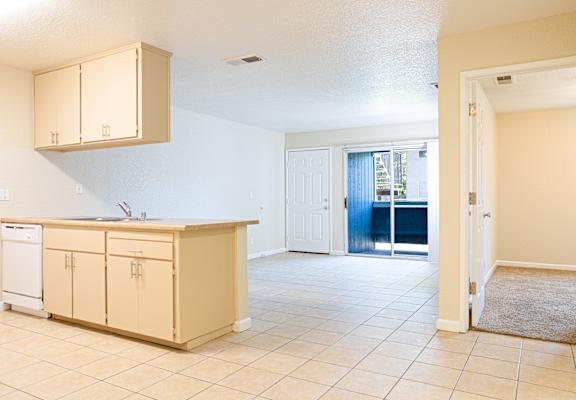 A kitchen with beige cabinets and a white dishwasher.