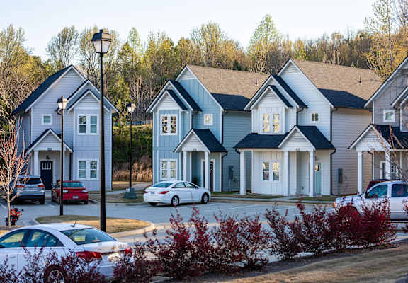 A row of houses with cars parked in front.