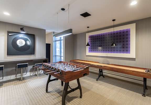 A room with a pool table and a purple wall hanging.