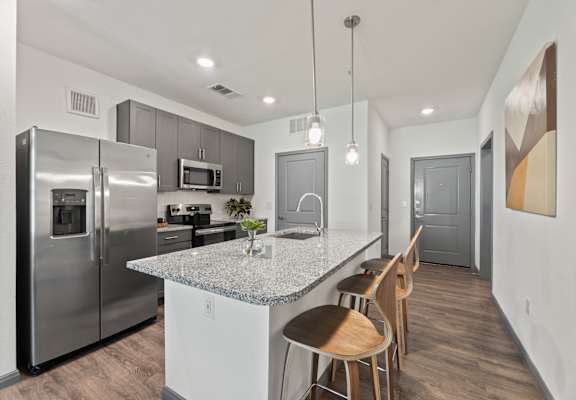 A kitchen with a granite countertop and stainless steel appliances.