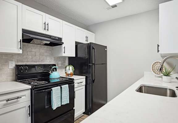 an apartment kitchen with black appliances and white cabinets