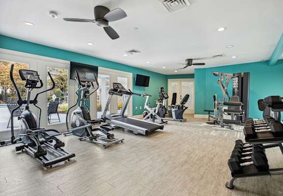 a gym with treadmills and other exercise equipment in a room with blue walls