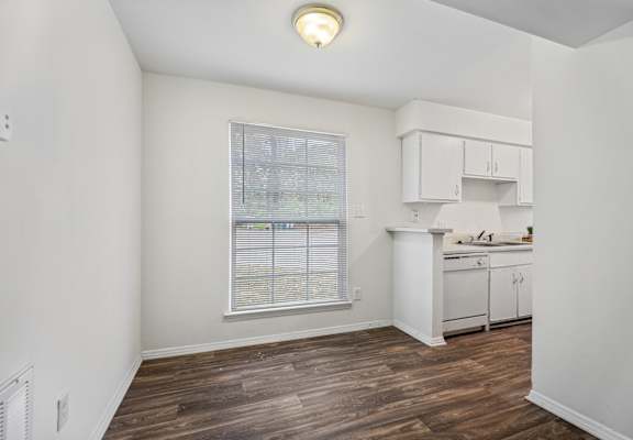 an empty kitchen with white cabinets and a large window