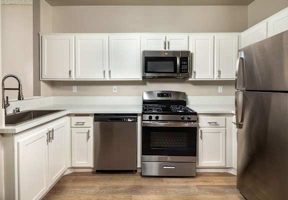 A kitchen with a stainless steel refrigerator, oven, and microwave.