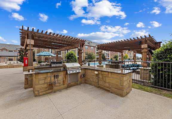 Outdoor grilling stations by the resort-style pool at Auberge of Burleson apartments in Burleson TX.