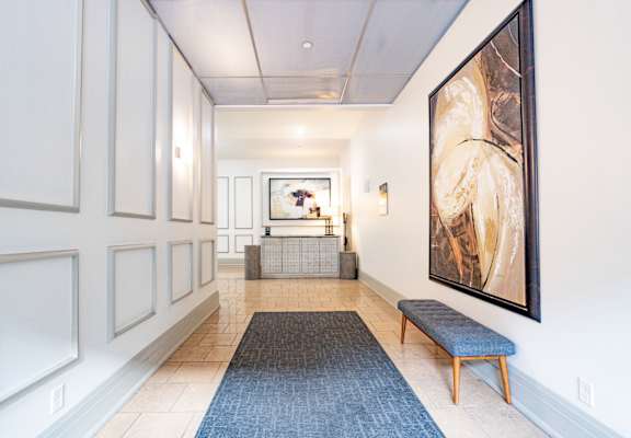 a view down a hallway with a bench and a large painting on the wall at 26 West, Managed by Buckingham Urban Living, 26 West Washington Street, IN