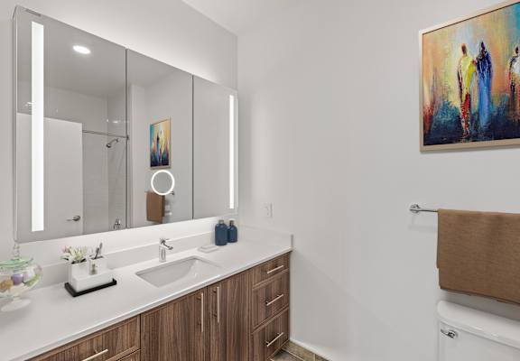 A bathroom with a large mirror, a sink, and a painting on the wall.