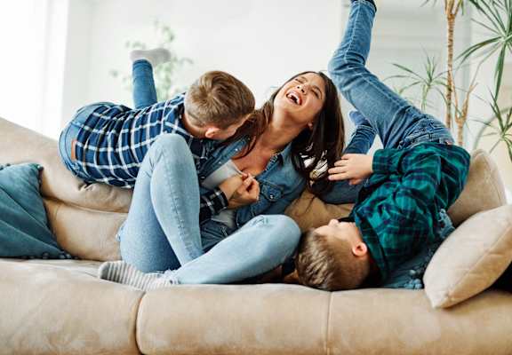 A family of three is lying on a beige couch at Ridge Crossings Apartments, Hoover, AL 35244