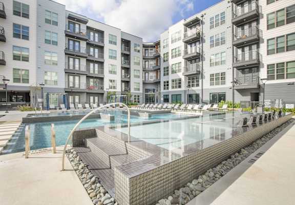 a swimming pool with an apartment building in the background