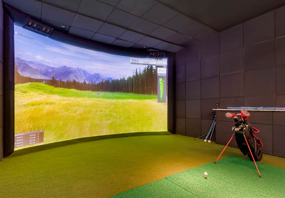 a golf simulator in a room with a view of a golf course