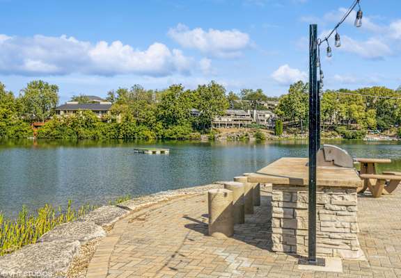 a picnic table on a stone patio overlooking a lake at Runaway Bay Apartments, Columbus, OH