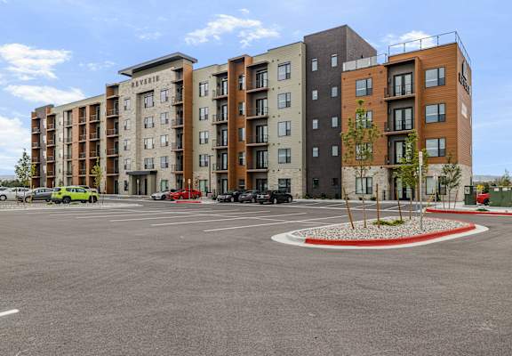 A parking lot in front of a multi-story apartment building.