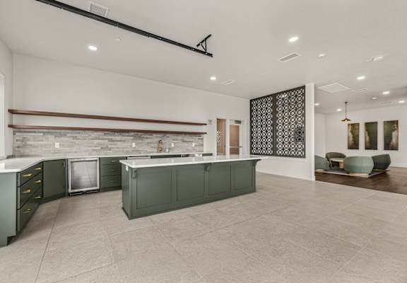 A modern kitchen with dark green cabinets and a stone backsplash.