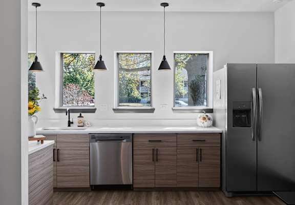 A modern kitchen with a refrigerator, sink, and cabinets.