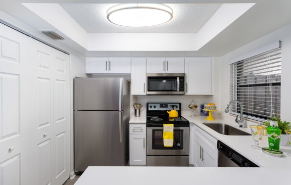 A kitchen with white cabinets and stainless steel appliances. at Boca Colony Apartments, Florida