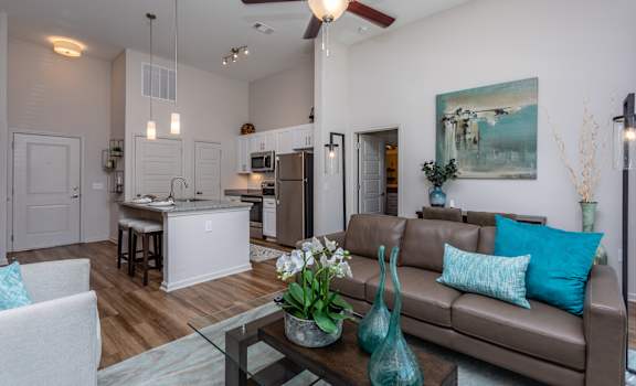 A modern living room with a brown couch and a glass coffee table.