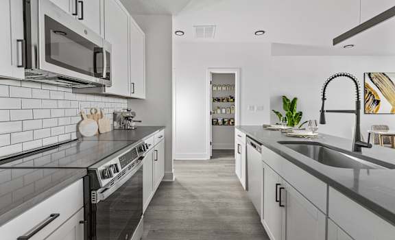 A modern kitchen with white cabinets and black countertops.
