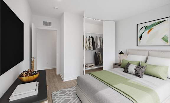 A bedroom with a large bed and a closet with clothes hanging.