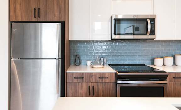 a modern kitchen with stainless steel appliances and white cabinets at The Press/321, Detroit MI