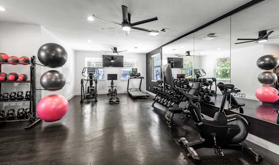 A gym with a row of exercise bikes and a mirror on the wall.