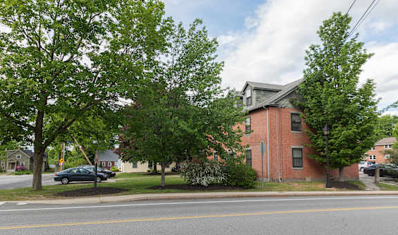 a red brick apartment complex with trees in front of it