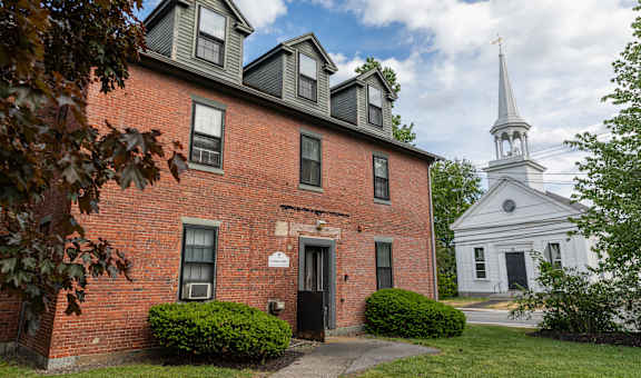 a brick building with a white church steeple in the background