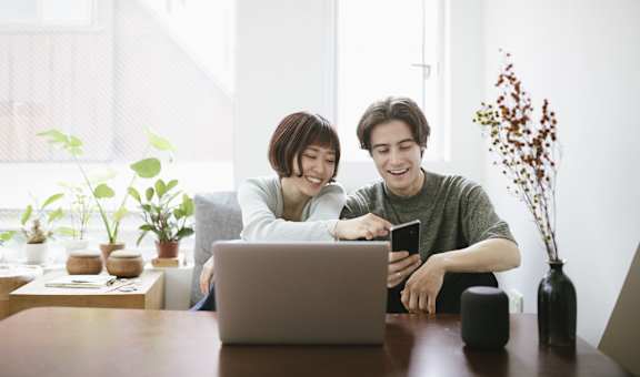 two people sitting at a table looking at a laptop