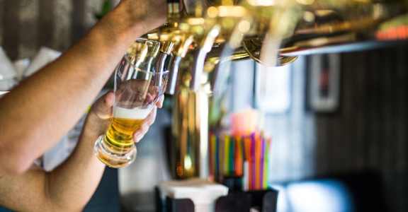 Person pouring a glass of beer in a bar