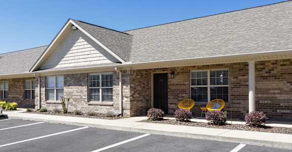 a brick building with chairs on front porch at Deerfield Apartments in Florence, AL
