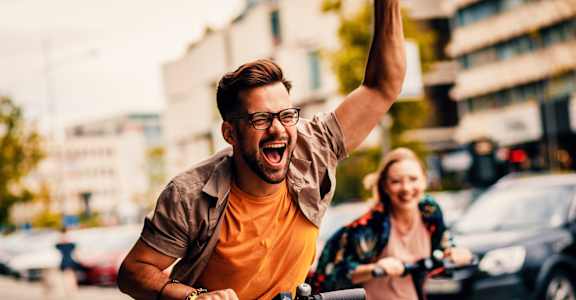 a man riding a bike down the street with a woman on a bike