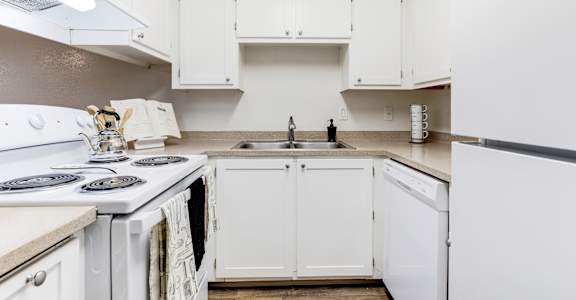 a kitchen with white cabinets and appliances and a sink