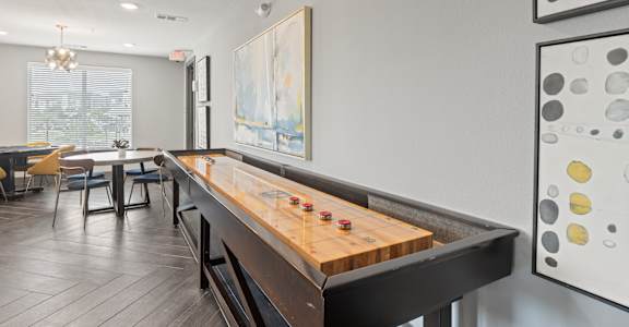 A shiny wooden pool table in a room with a painting on the wall.