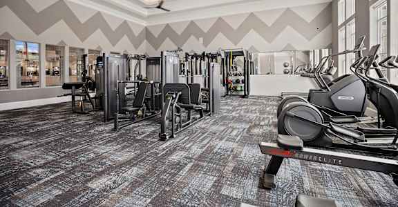 a gym with weights and cardio equipment in a building with large windows at Ellis Station, Durham