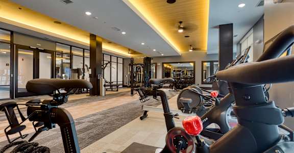 a gym with exercise bikes and other equipment on the floor and windows at Aura Stonebridge, Richmond