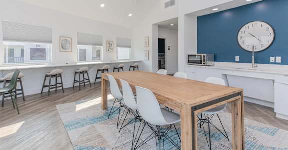 a dining room with a table and chairs and a clock on the wall