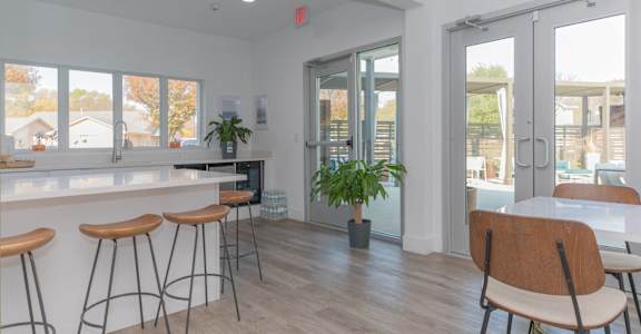 a kitchen with a bar and stools in front of a window