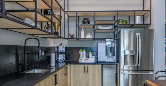 A modern kitchen with a black countertop and stainless steel appliances.
