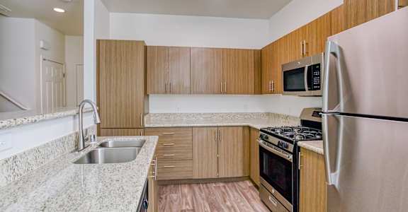 A kitchen with a refrigerator, sink, and stove.