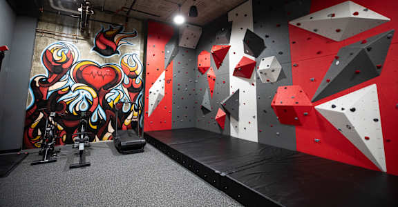 A climbing wall with a red and black color scheme and a mural on the wall at Cityplace Apartment Homes Apartments, Allentown, PA, 18101